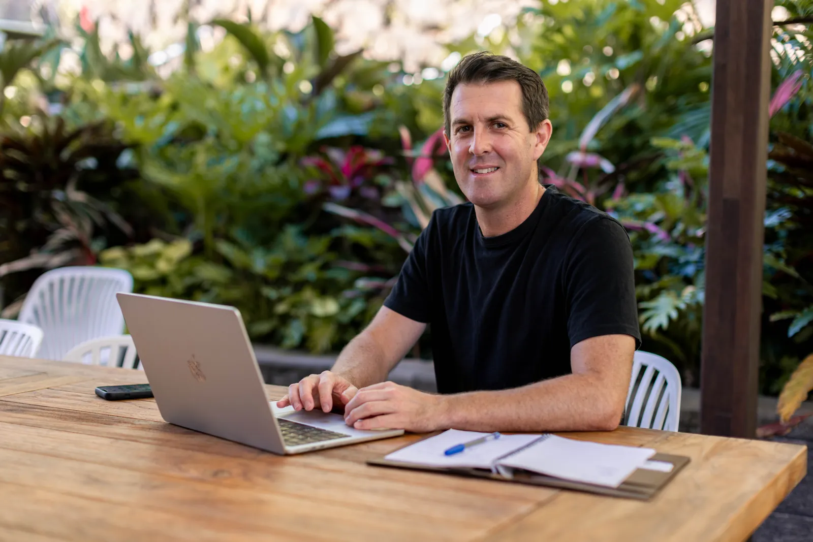 Chris, the founder of The Hands-Off Business Blueprint, working at his outdoor desk
